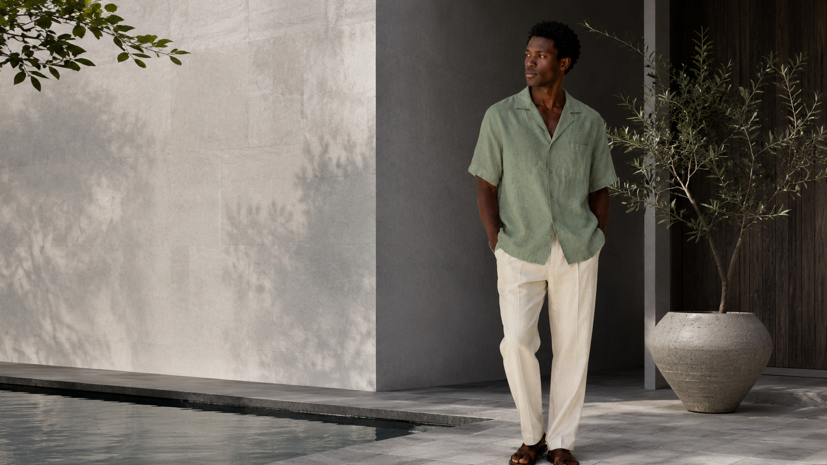 Model on rocky shoreline in striped linen shirt and cream trousers